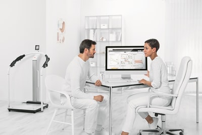 穿着白衬衫的男人坐在电脑前的白色椅子上